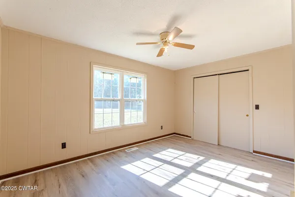 a view of empty room with wooden floor and fan
