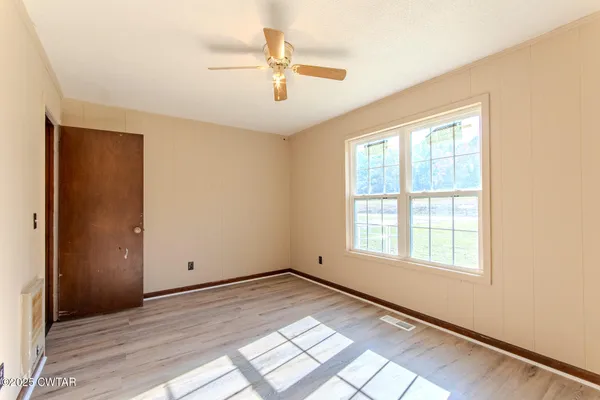 an empty room with a window and ceiling fan