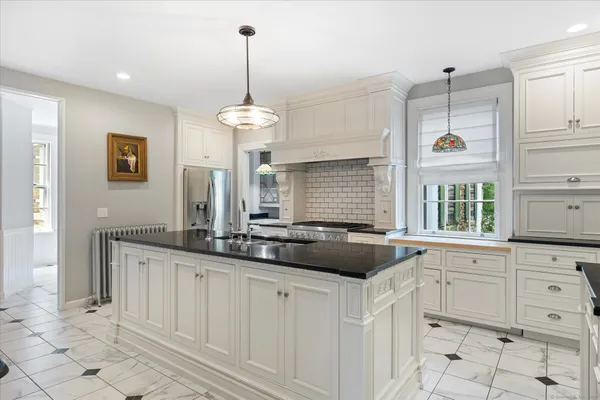 a kitchen with white cabinets and window