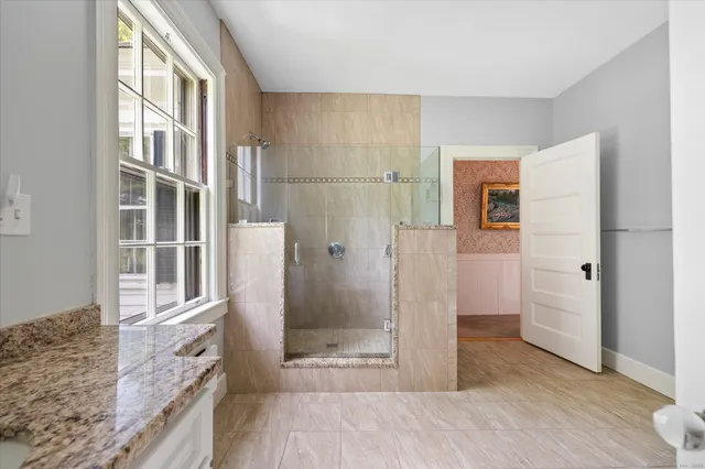 a bathroom with a granite countertop shower a sink and a mirror