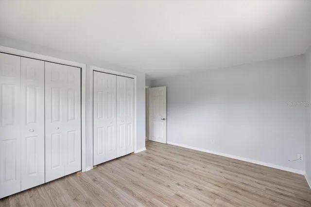 a view of an empty room and a kitchen with wooden floor and a ceiling fan