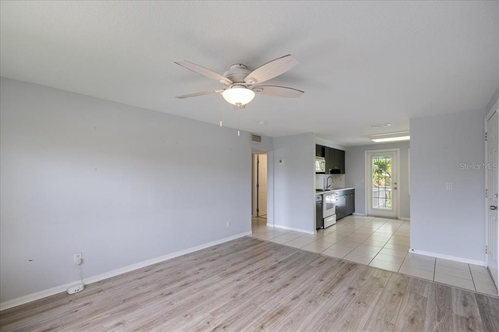307 Winfield Way Nokomis, FL 34275 - Photo 31 of 58 a view of an empty room and a kitchen with wooden floor and a ceiling fan