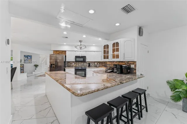 a large kitchen with granite countertop a sink and cabinets