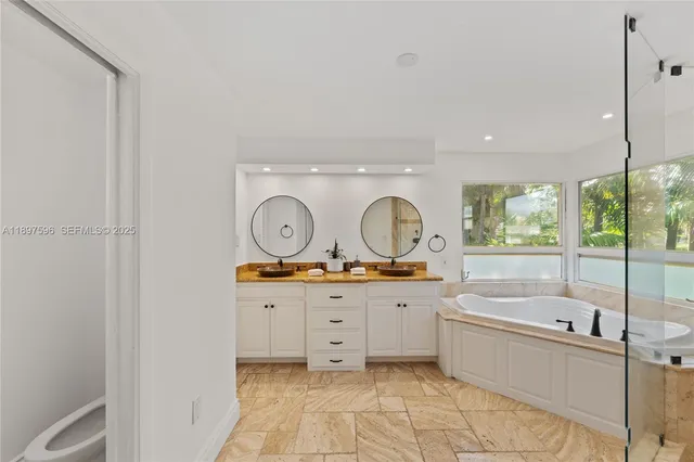 a large bathroom with a tub sink and mirror