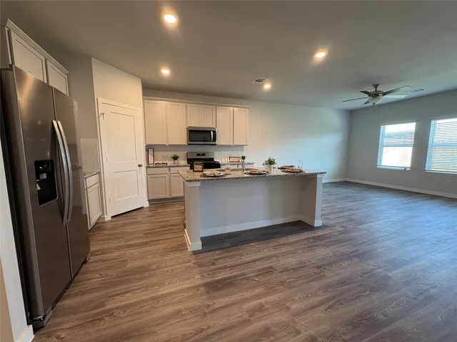 a kitchen with stainless steel appliances granite countertop a refrigerator a sink a stove and oven