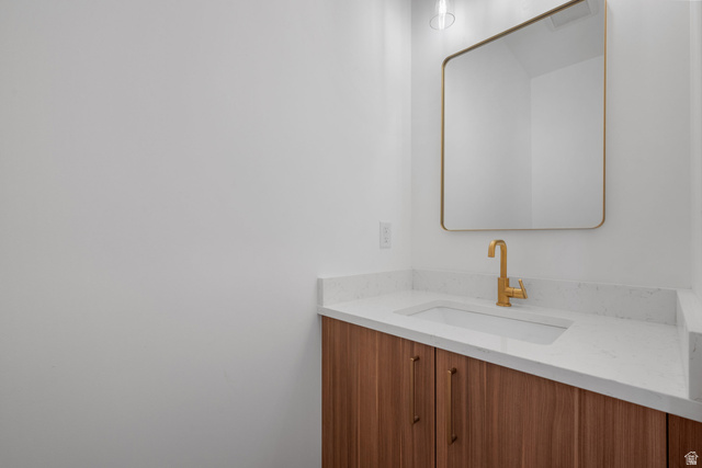 7238 South 525 East Midvale, UT 84047 - Photo 10 of 29 Vanity featuring a wood-finish cabinet, gold-finish hardware, and a white countertop with an integrated rectangular sink