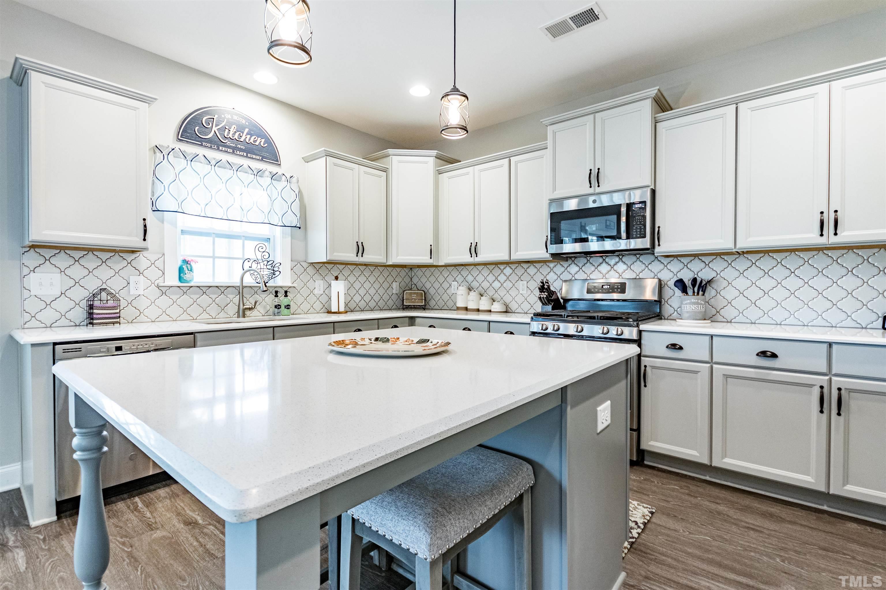460 Mallard Loop Drive Clayton, NC 27527 - Photo 13 of 24 a kitchen with kitchen island a stove a sink a microwave and cabinets