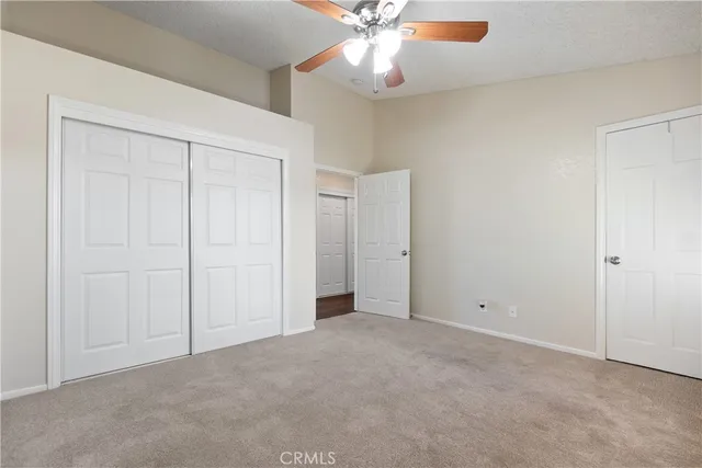 an empty room with closet and a chandelier fan