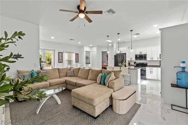 a living room with furniture kitchen view and a potted plant