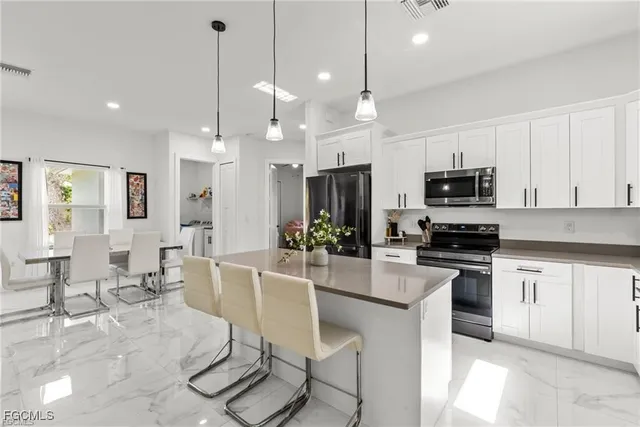 a large kitchen with kitchen island granite countertop a large center island a stove a dining table and chairs