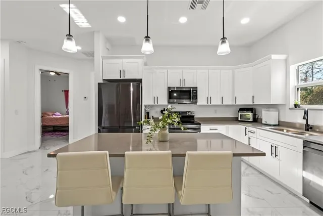 a large kitchen with kitchen island a large counter top space appliances and cabinets