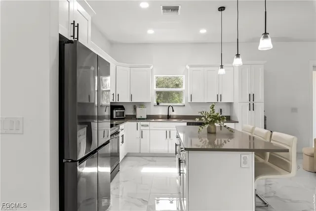 a kitchen with kitchen island granite countertop a sink cabinets and refrigerator