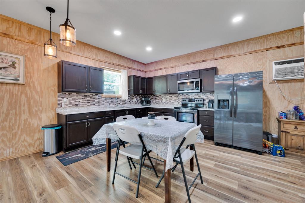 2263 Old Dicey Road Weatherford, TX 76085 - Photo 31 of 40 a kitchen with stainless steel appliances granite countertop a stove top oven a refrigerator a sink and chairs