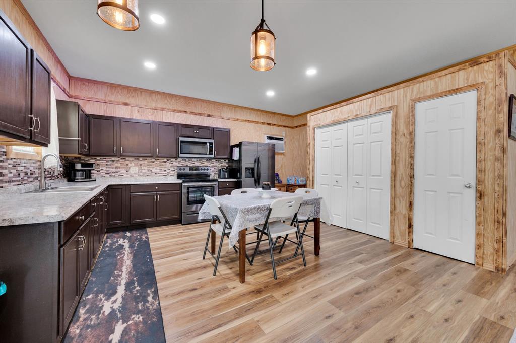 2263 Old Dicey Road Weatherford, TX 76085 - Photo 32 of 40 a kitchen with stainless steel appliances kitchen island granite countertop a stove top oven a sink a dining table and chairs with wooden floor