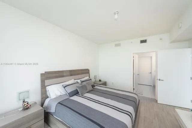 a bedroom with a bed and a lamp on the dresser