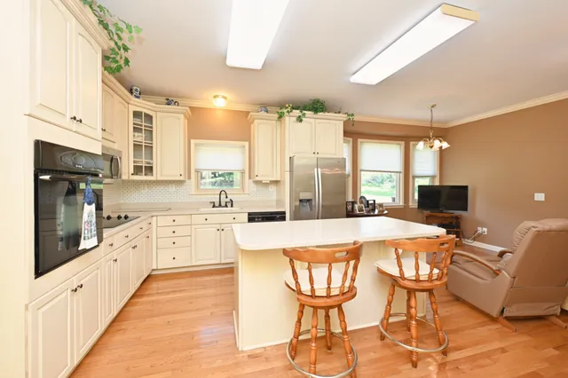 a kitchen with stainless steel appliances kitchen island granite countertop a table chairs and a refrigerator