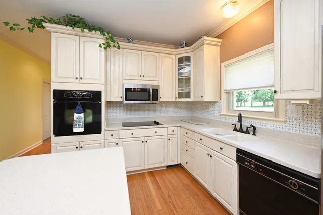 a kitchen with granite countertop a sink stainless steel appliances and white cabinets