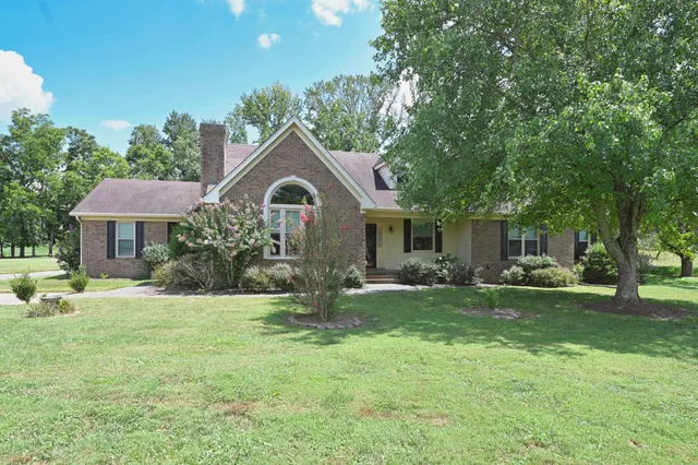 a front view of a house with a garden and trees
