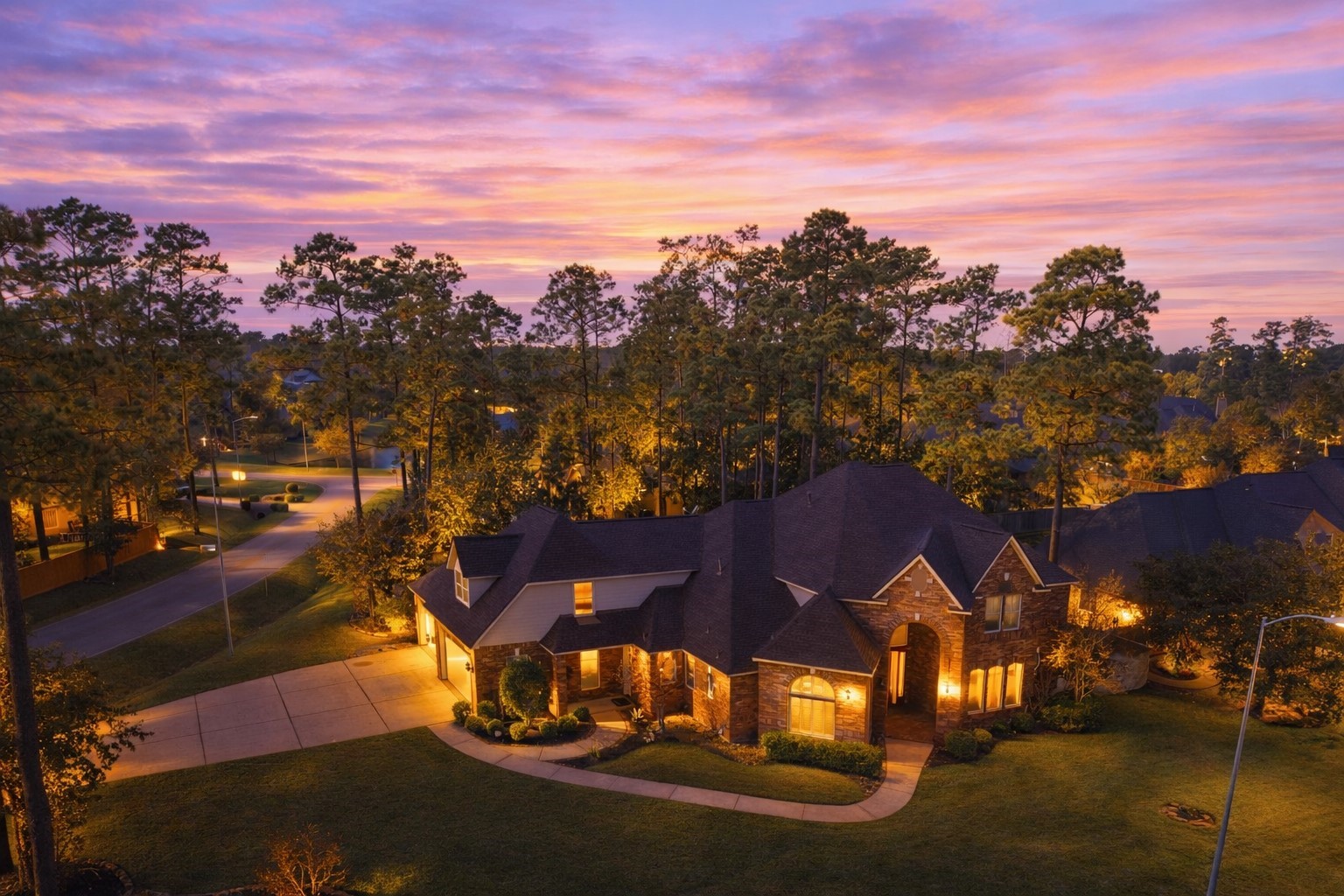 Stunning curb appeal on a spacious corner lot, featuring a grand brick exterior, manicured landscaping and towering trees.