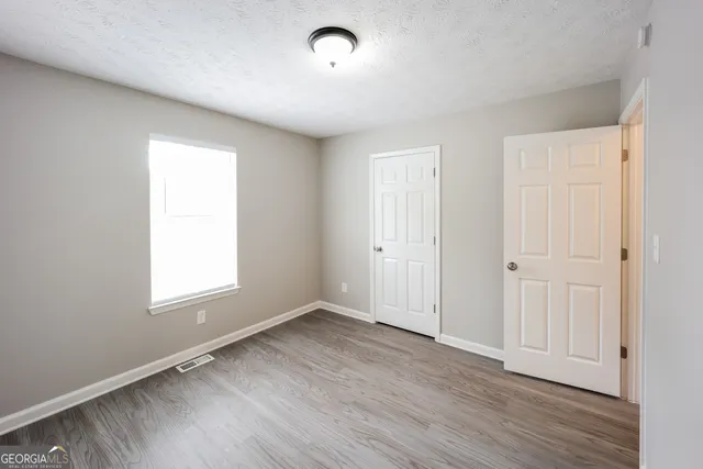 an empty room with wooden floor and windows