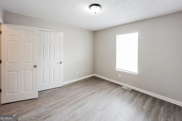 an empty room with wooden floor and windows