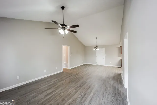a view of an empty room with a ceiling fan and wooden floor