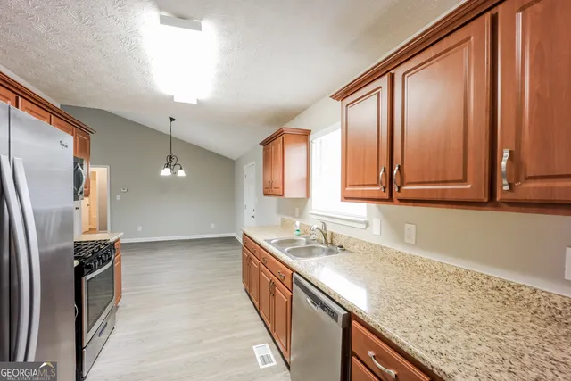 a kitchen with stainless steel appliances granite countertop a sink and a refrigerator