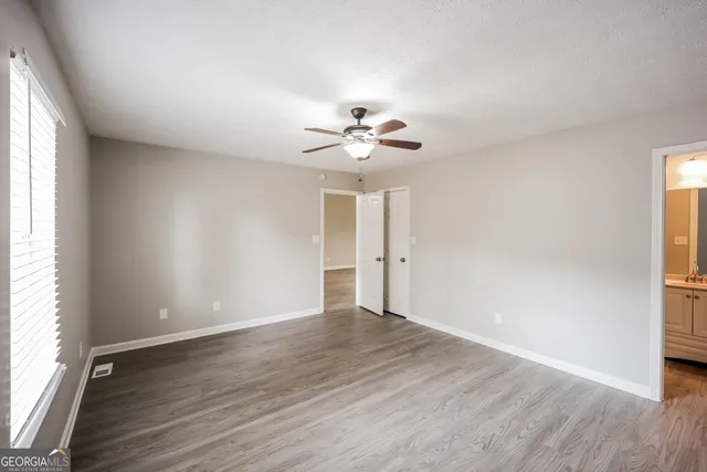 an empty room with wooden floor and ceiling fan