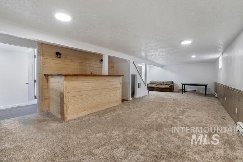 201 East 27th Street Burley, ID 83318 - Photo 15 of 19 Additional living space with light carpet, a textured ceiling, and wood walls