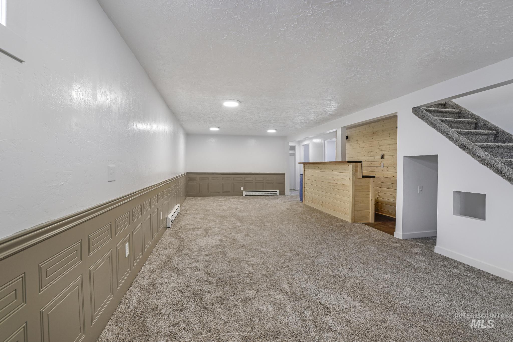 201 East 27th Street Burley, ID 83318 - Photo 16 of 19 Finished below grade area with a wainscoted wall, carpet flooring, a textured ceiling, recessed lighting, and a baseboard radiator
