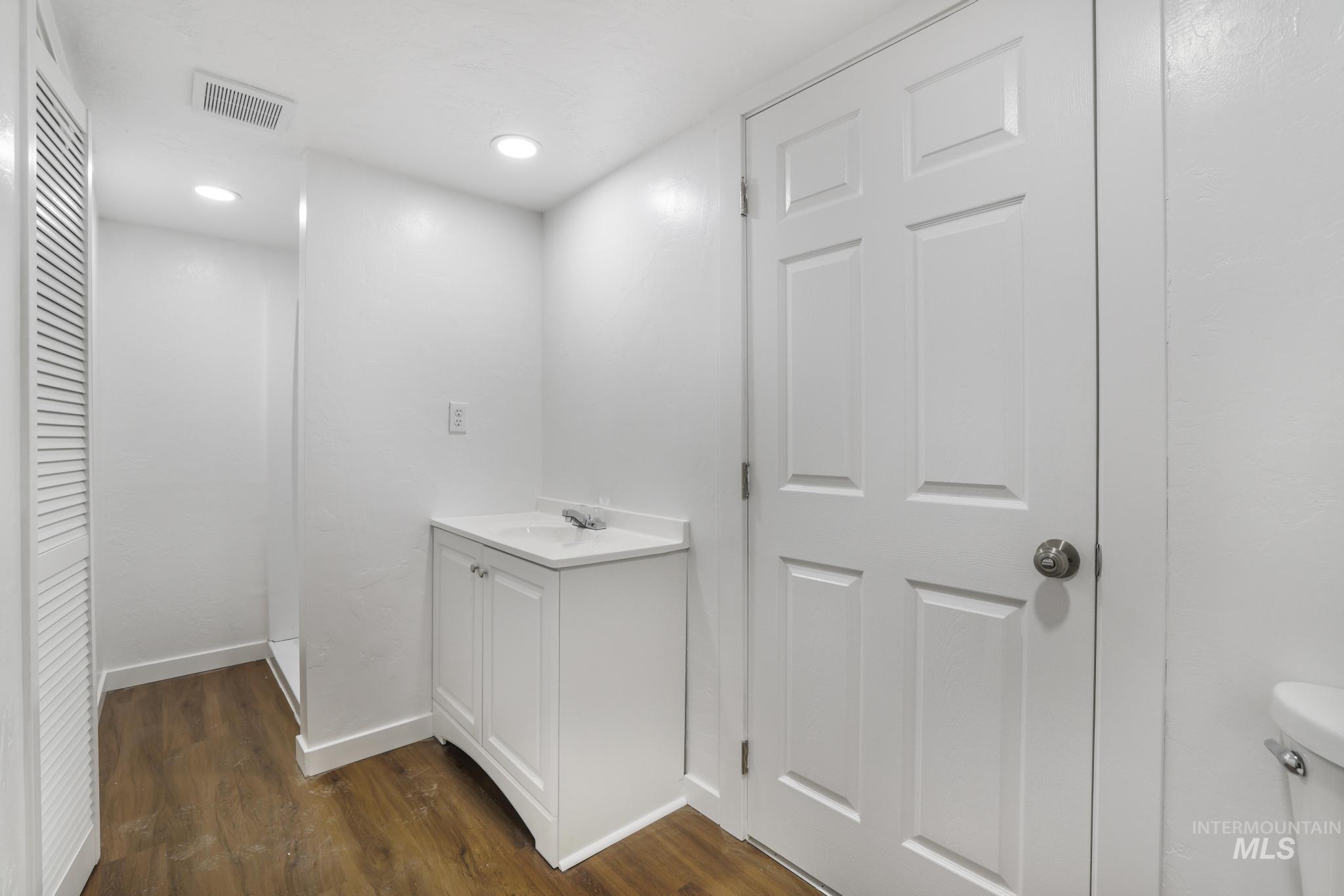 201 East 27th Street Burley, ID 83318 - Photo 17 of 19 Bathroom featuring dark wood finished floors, vanity, recessed lighting, and a closet