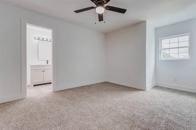 an empty room with chandelier fan and windows