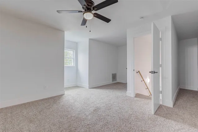an empty room with a ceiling fan and carpet