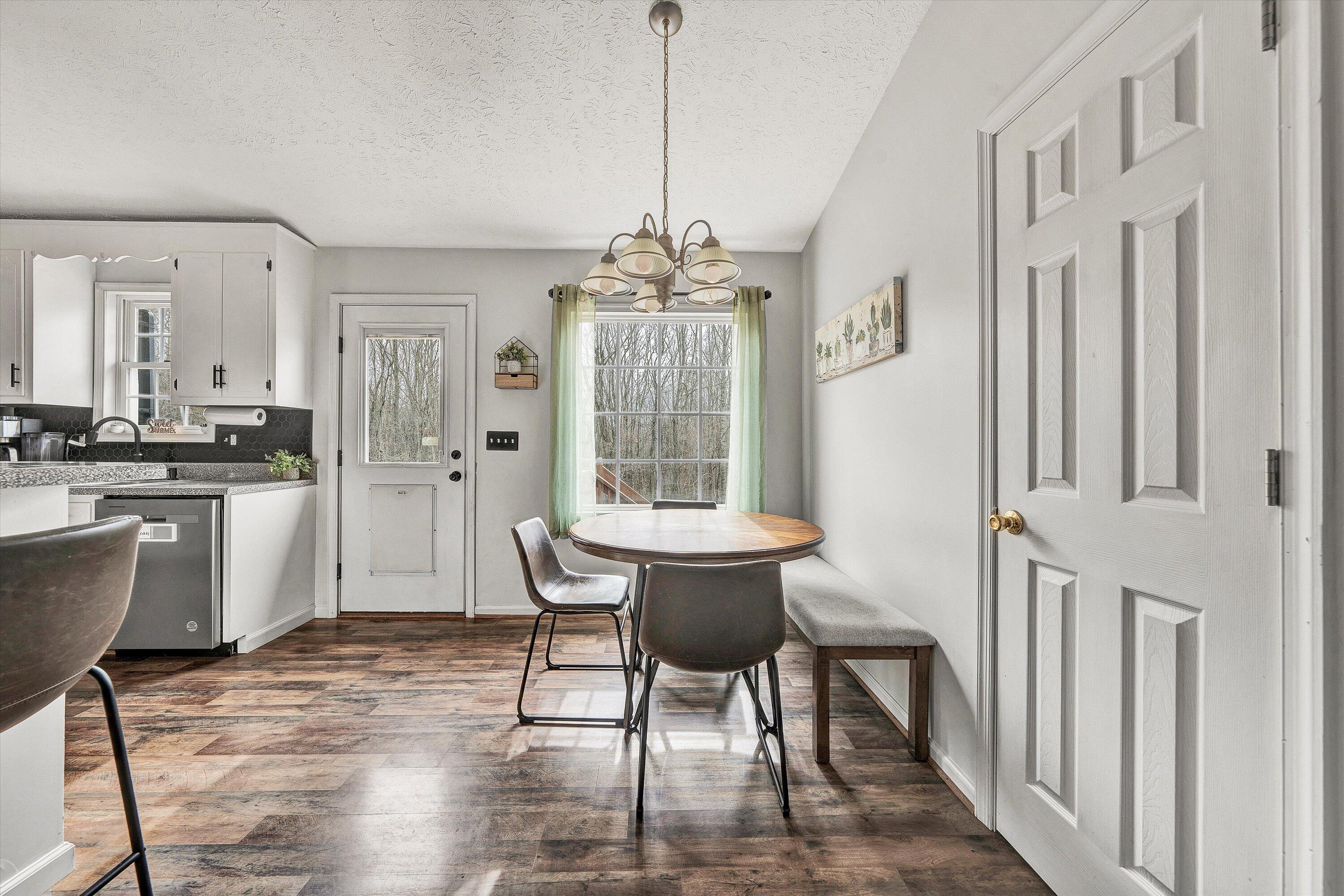 1188 Airport Road Moneta, VA 24121 - Photo 12 of 34 a dining room with wooden floor a chandelier a wooden table and chairs