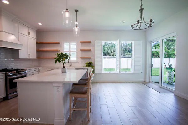a kitchen with kitchen island granite countertop a stove a sink a center island and wooden floor