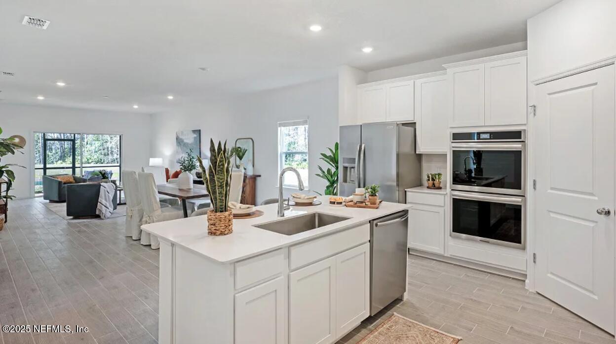 24 Bluegrass Way St. Augustine, FL 32092 - Photo 8 of 39 a kitchen with stainless steel appliances kitchen island granite countertop a refrigerator oven a sink dishwasher and white cabinets with wooden floor