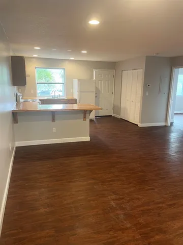 a view of kitchen and empty room with wooden floor