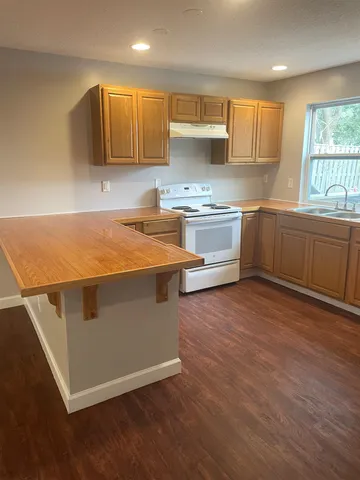 a kitchen with granite countertop a stove and a wooden floors