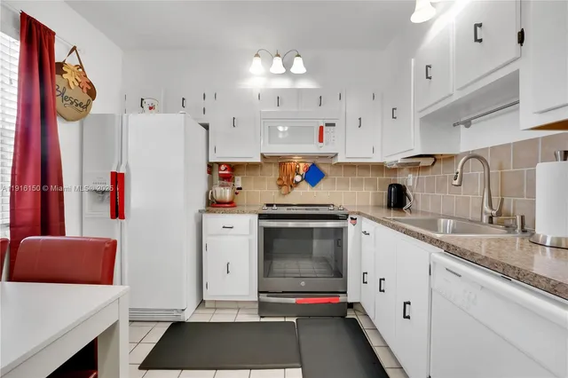 a kitchen with granite countertop a white refrigerator and a stove with wooden floor