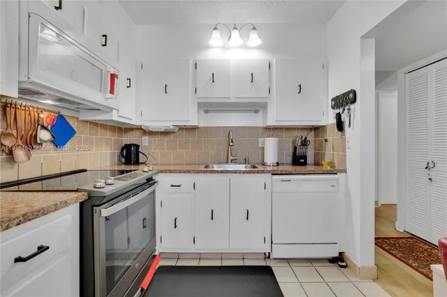 a kitchen with granite countertop white cabinets and white appliances