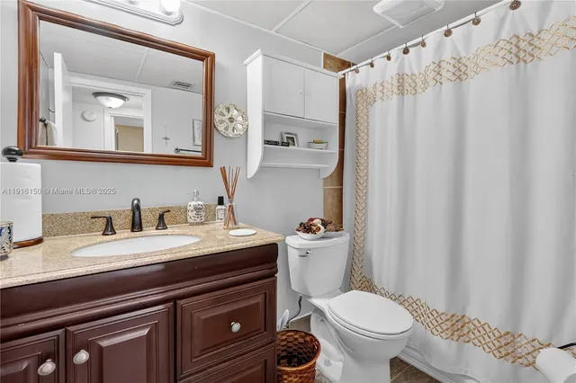 a bathroom with a granite countertop toilet sink and mirror