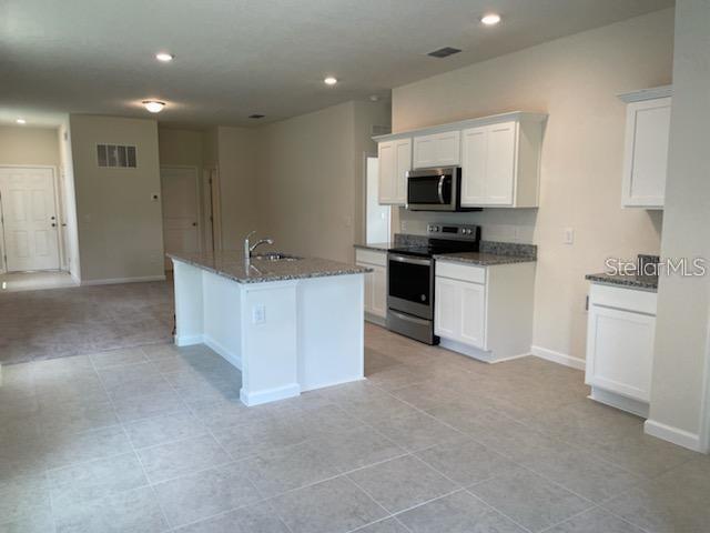 2332 Litchfield Loop DeLand, FL 32720 - Photo 3 of 15 a kitchen with stainless steel appliances kitchen island sink refrigerator and stove