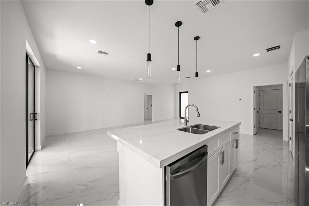 3315 67th Street West Lehigh Acres, FL 33971 - Photo 11 of 38 Kitchen with open floor plan, stainless steel appliances, white cabinets, pendant lighting, and light stone counters