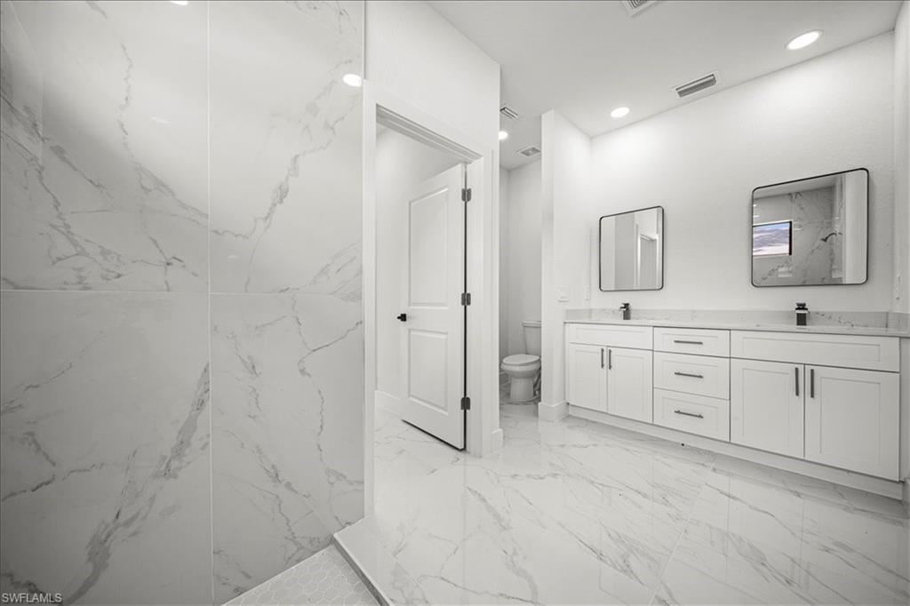 3315 67th Street West Lehigh Acres, FL 33971 - Photo 20 of 38 Bathroom featuring double vanity, a marble finish shower, light marble finish floors, and recessed lighting