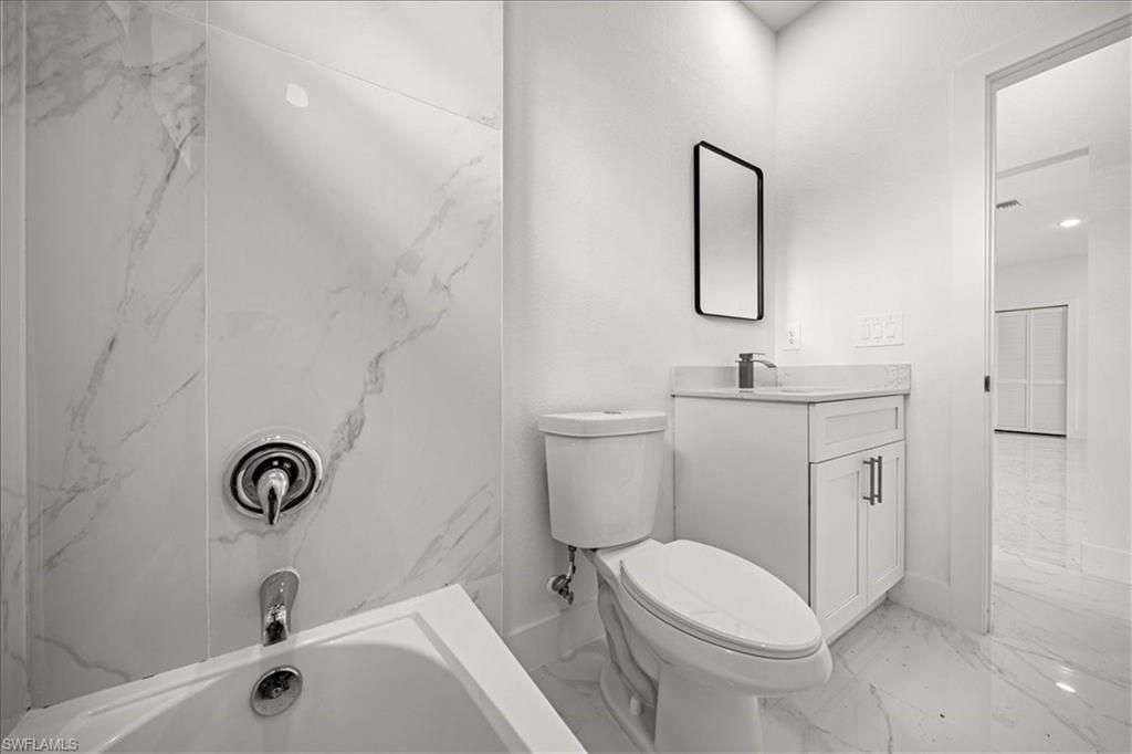 3315 67th Street West Lehigh Acres, FL 33971 - Photo 26 of 38 Bathroom featuring light marble finish floors, vanity, and tub / shower combination
