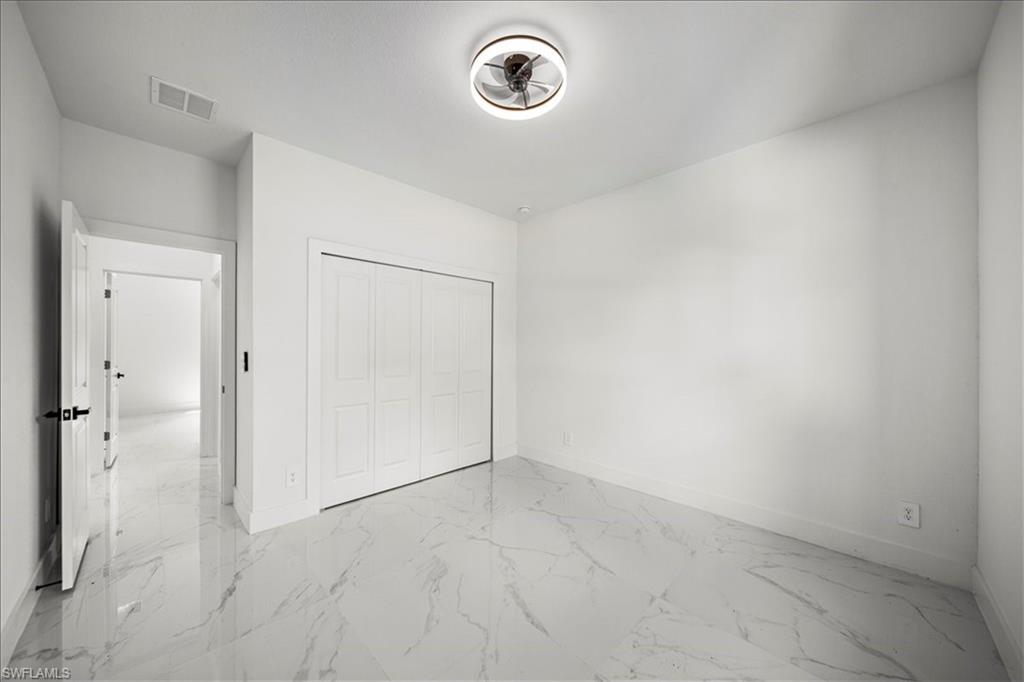 3315 67th Street West Lehigh Acres, FL 33971 - Photo 28 of 38 Unfurnished bedroom featuring light marble finish floors and a closet