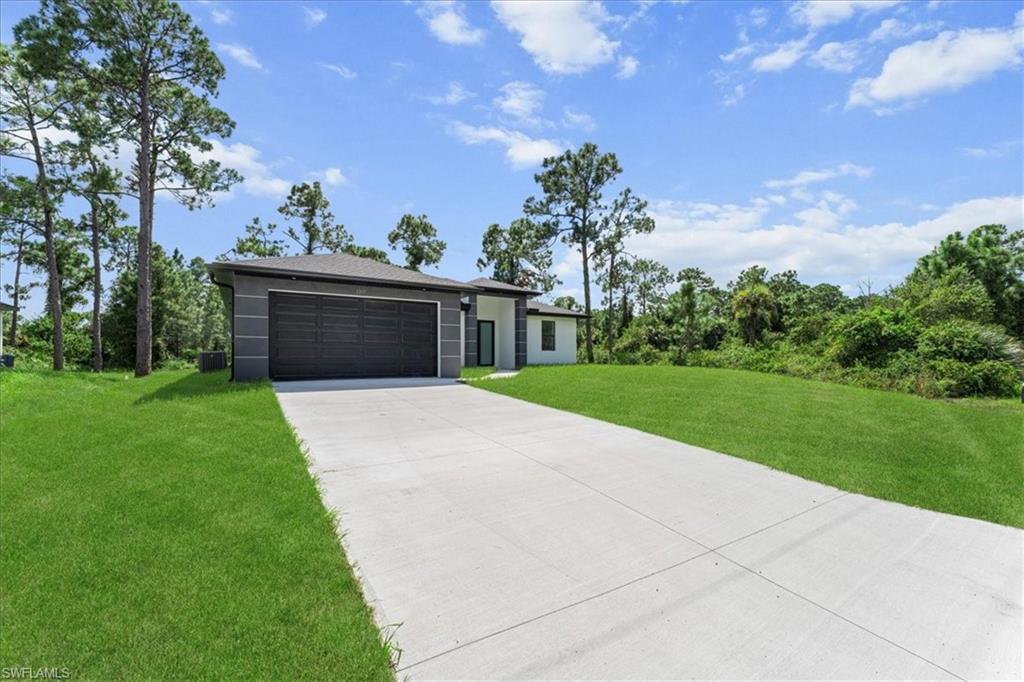 3315 67th Street West Lehigh Acres, FL 33971 - Photo 31 of 38 View of front of property featuring a front lawn, concrete driveway, and an attached garage