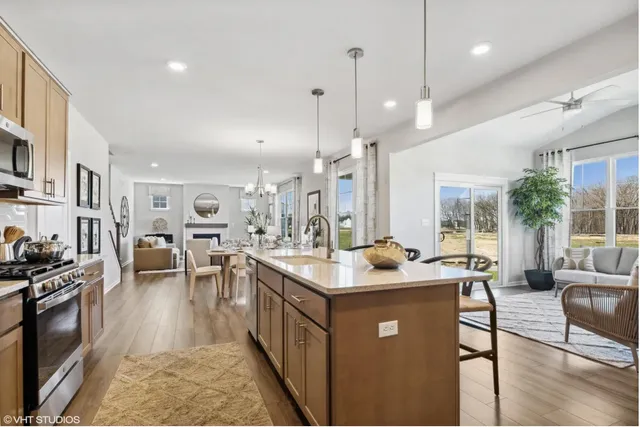 a kitchen with stainless steel appliances granite countertop a stove top oven a sink a counter top space and living room view