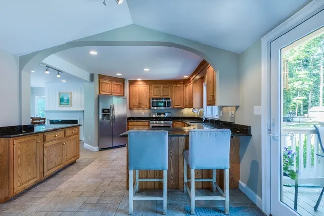 a kitchen with stainless steel appliances kitchen island granite countertop a table chairs sink and cabinets