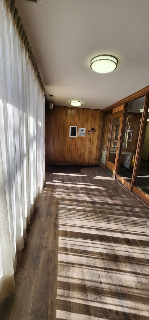 7730 Dempster Street, Unit 209 Morton Grove, IL 60053 - Photo 28 of 32 a view of an empty room with wooden floor and a window